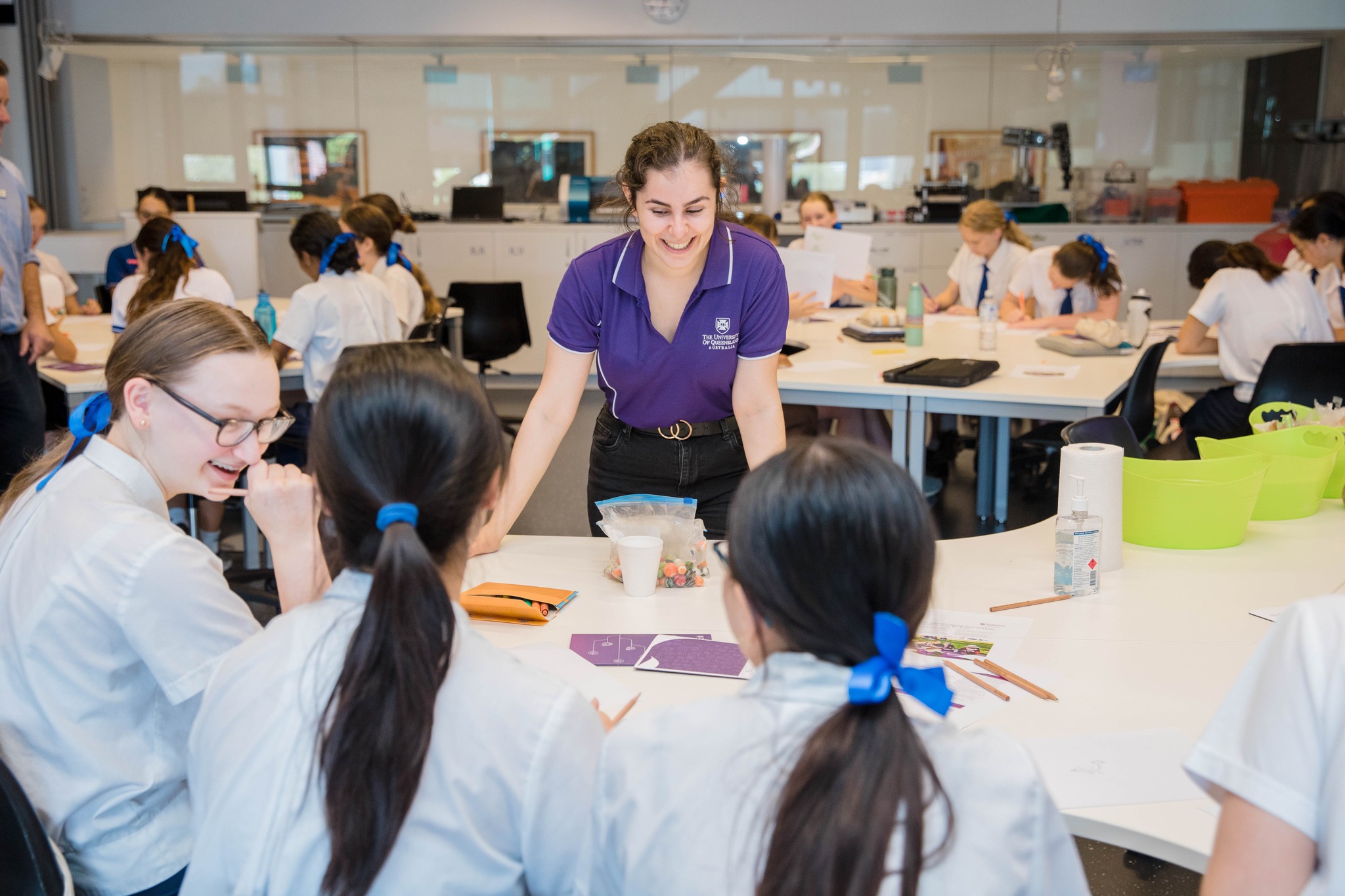 A person standing in front of small table group in a classroom having a group discussion.