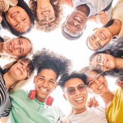 Low angle of a group of students are together, happy and smiling. Faces of young teenagers looking at camera, hugging.